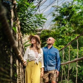Couple walking across a wobbly bridge in the Rainforest Biome